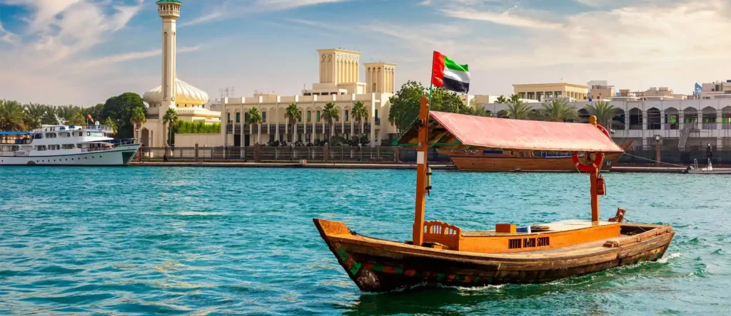 Traditional wooden abra boat cruising along Dubai Creek with city skyline in the background